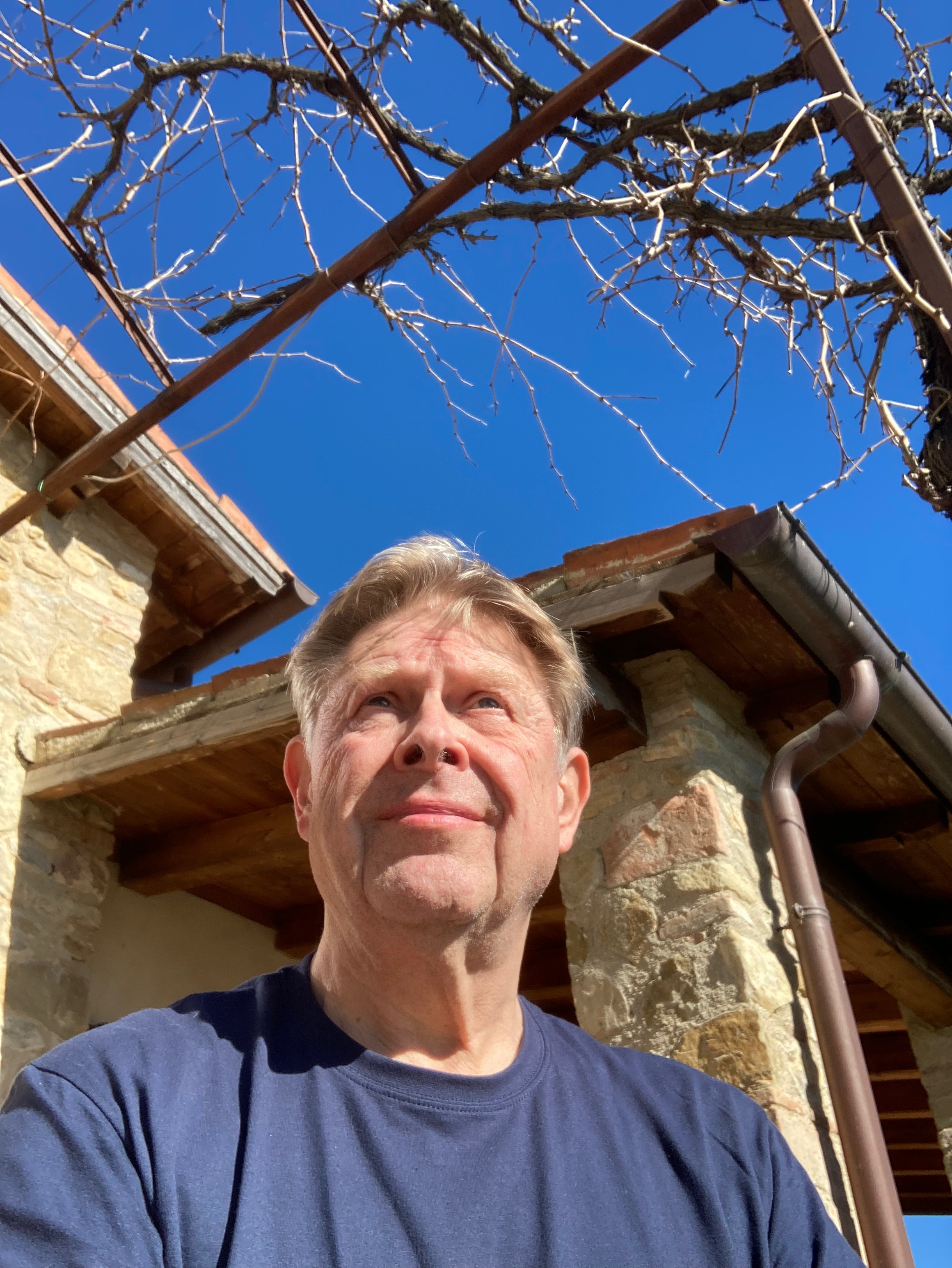Autor vor Haus und blauem Himmel